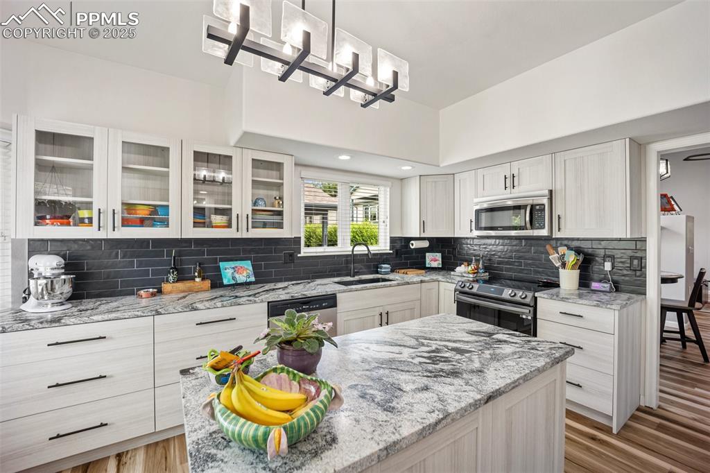 Image 15 of 50: Kitchen featuring appliances with stainless steel finishes, light wood-styl
