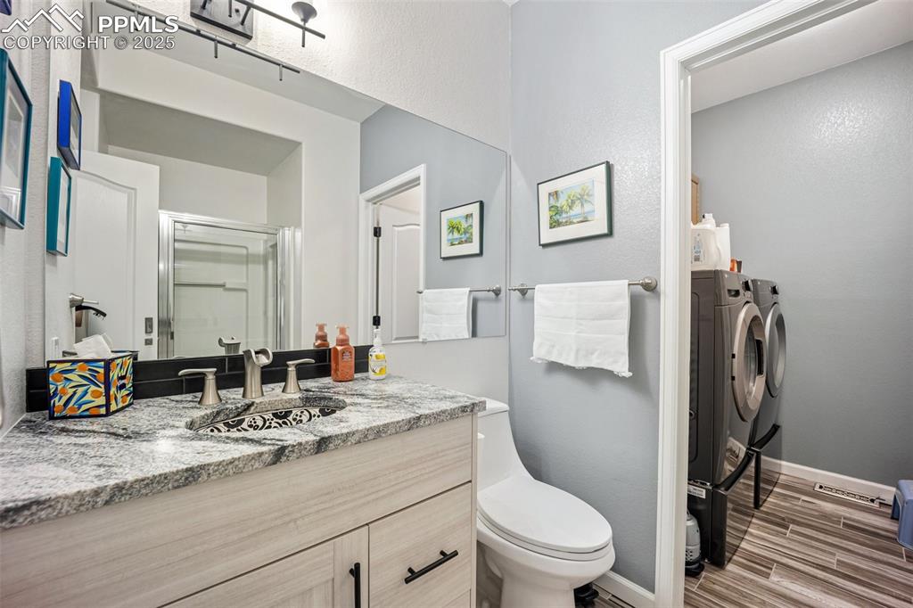 Image 24 of 50: Full bath featuring washer and clothes dryer, a shower stall, vanity, and w