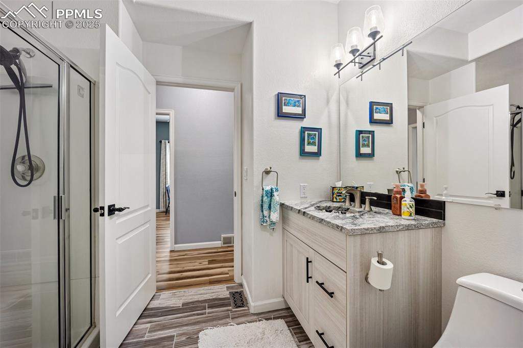 Image 25 of 50: Full bathroom with vanity, a stall shower, and wood finished floors