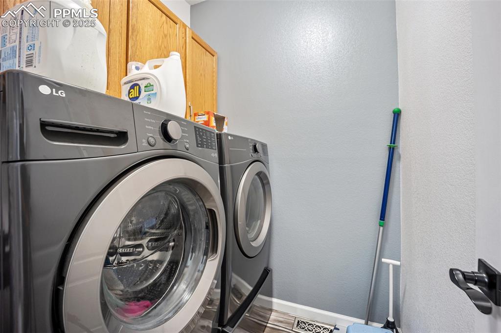 Image 26 of 50: Washroom featuring washer and clothes dryer and cabinet space