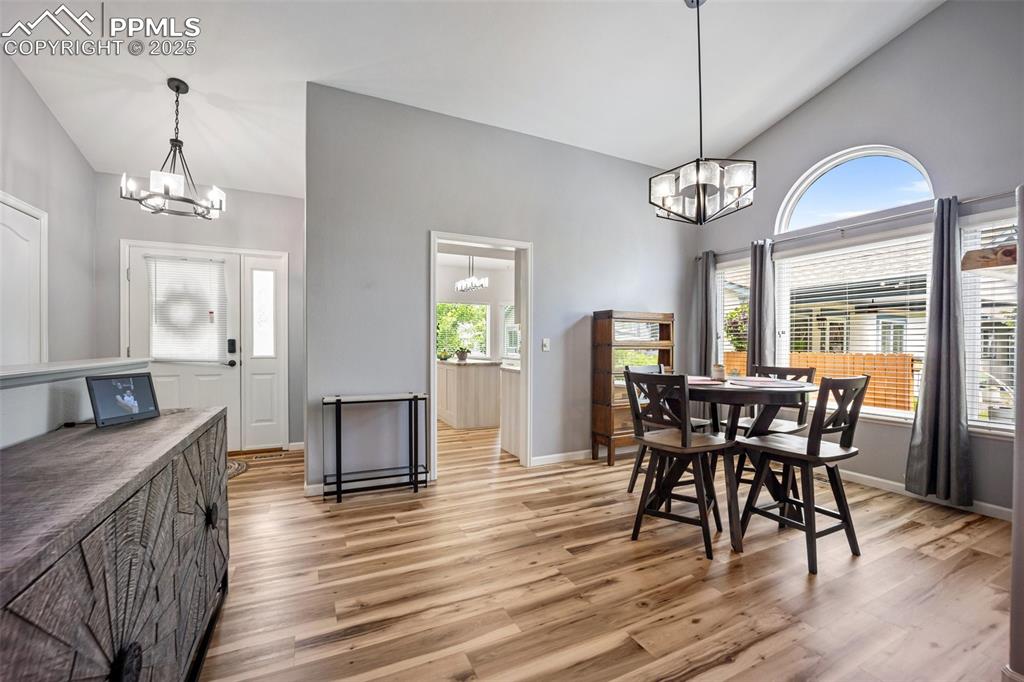 Image 3 of 50: Dining area featuring a chandelier, light wood-style flooring, and high vau