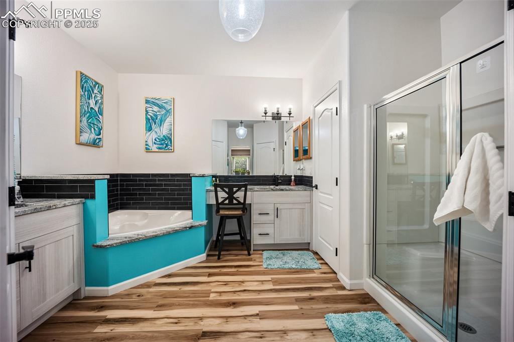 Image 31 of 50: Full bathroom featuring vanity, wood finished floors, a shower stall, and a