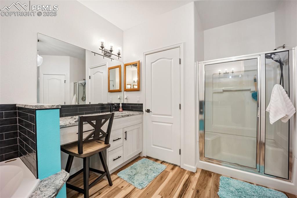 Image 32 of 50: Bathroom featuring a shower stall, vanity, wood finished floors, and a bath
