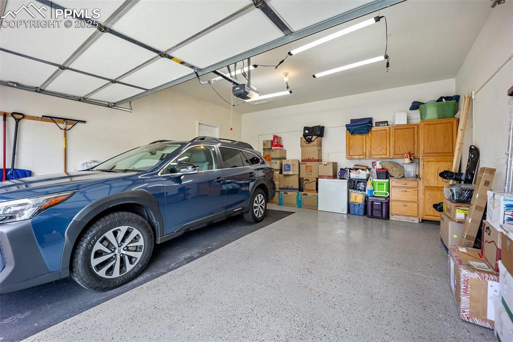 Image 42 of 50: Garage featuring a garage door opener and epoxy floors and work area