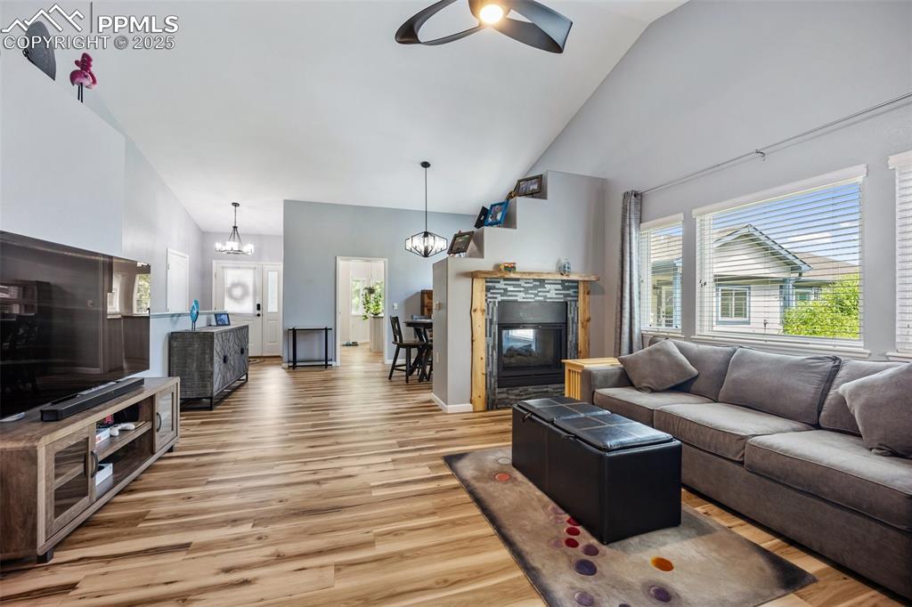 Image 6 of 50: Living room with high vaulted ceiling, a ceiling fan, light wood-type floor