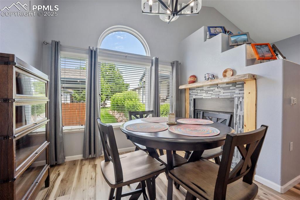 Image 8 of 50: Dining space featuring a chandelier, light wood-style floors, a stone firep