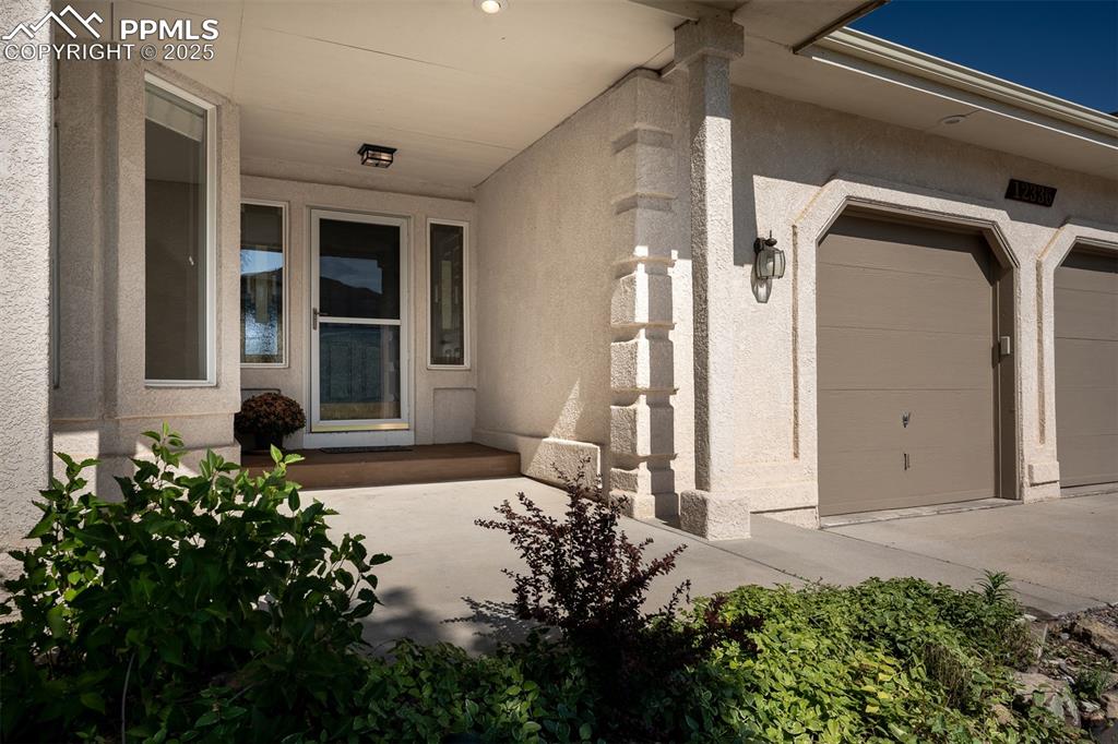 Image 5 of 50: Doorway to property featuring stucco siding and a garage