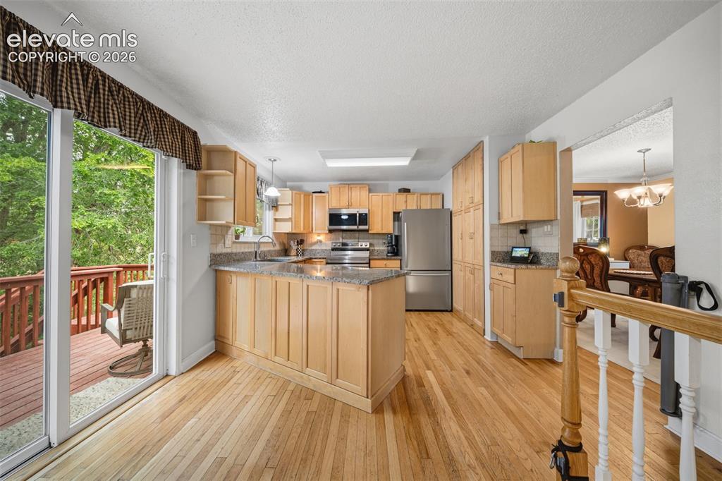 Image 11 of 42: Kitchen featuring light wood cabinetry, stainless steel appliances, granite