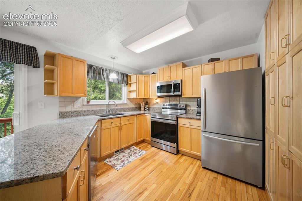 Image 12 of 42: Kitchen featuring wood-finish flooring and light wood cabinetry with brushe