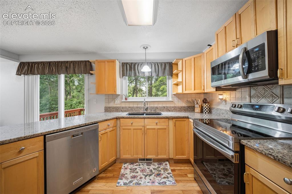 Image 13 of 42: Kitchen featuring wood-finish flooring, light wood cabinetry, stainless ste