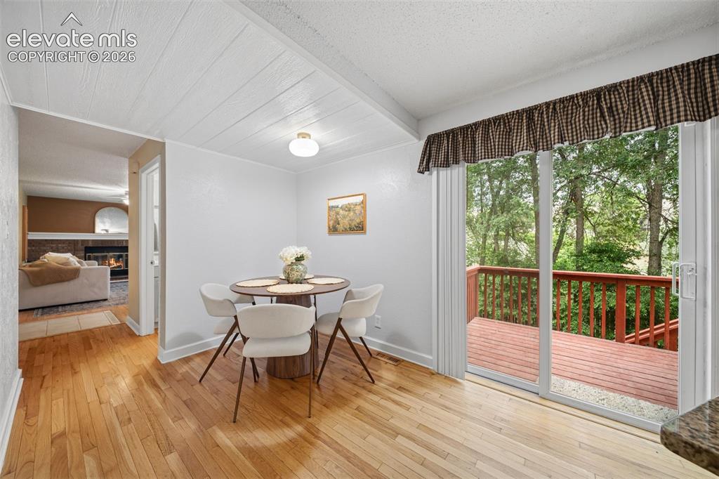 Image 15 of 42: Sliding glass door leading to an outdoor deck with wood railings, featuring