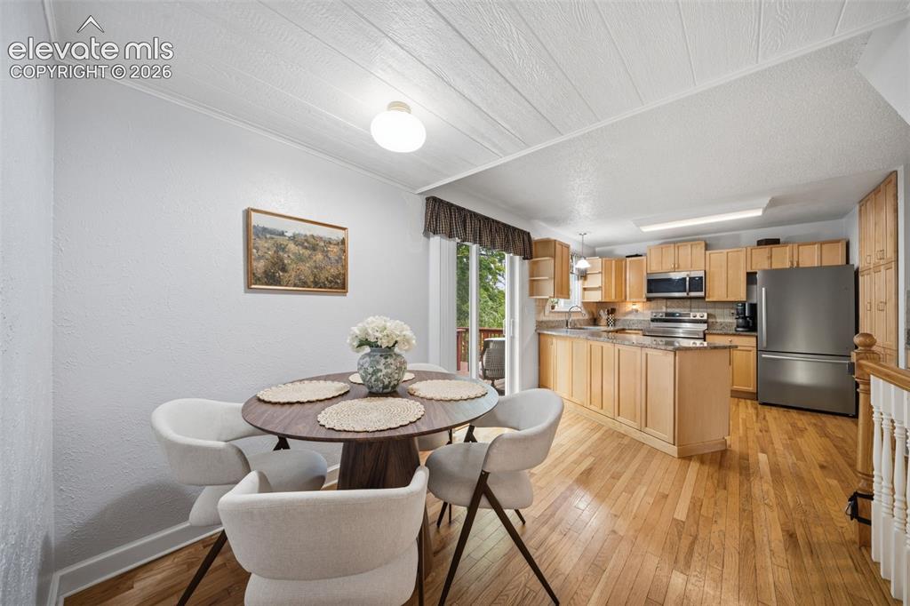Image 16 of 42: Open-concept kitchen and dining area featuring light wood cabinetry, stainl