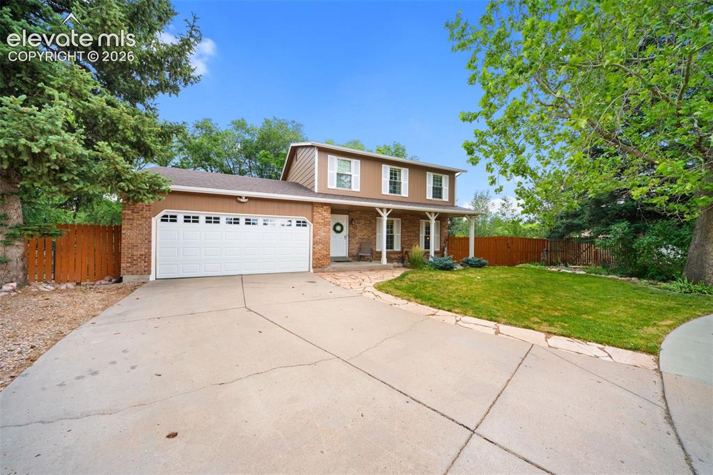 Image 2 of 42: Two-story home featuring a two-car garage with white panel door, brick faca