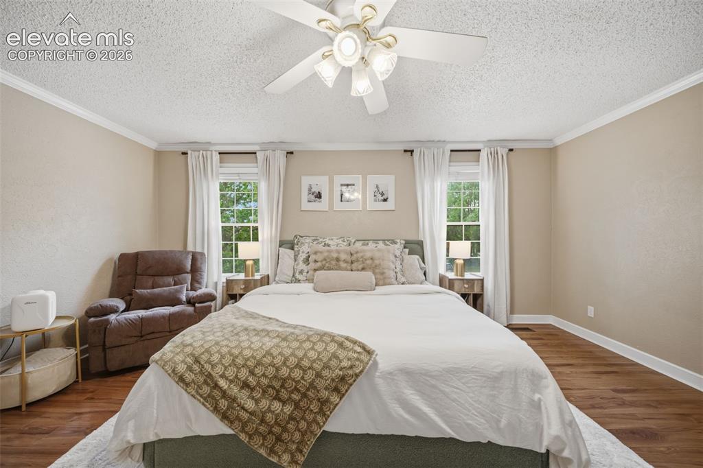 Image 20 of 42: Bedroom featuring wood-finish flooring, neutral wall tones, crown molding,