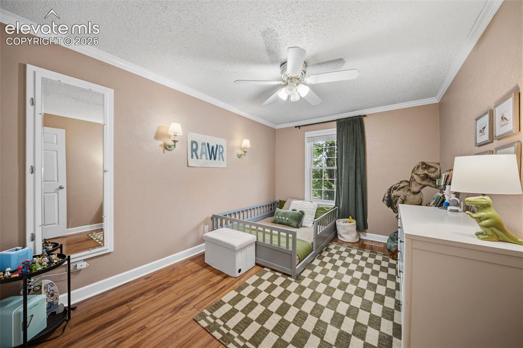 Image 23 of 42: Interior room featuring wood-finish flooring, crown molding, a ceiling fan