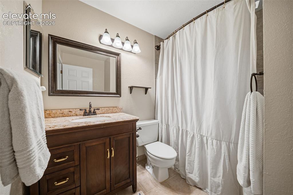 Image 25 of 42: Bathroom featuring a dark wood vanity with a granite countertop and undermo