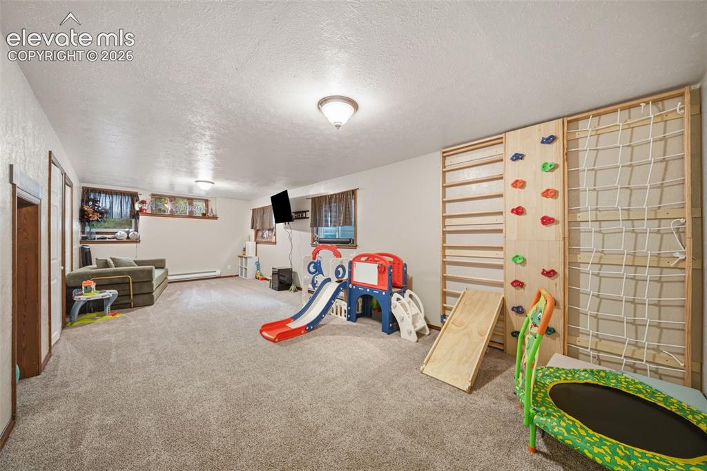 Image 28 of 42: Spacious room featuring light-colored carpet flooring, recessed wall shelvi