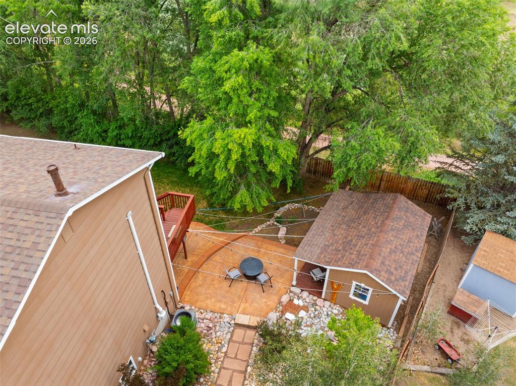 Image 34 of 42: Backyard area featuring a concrete patio, stone landscaping, and a detached
