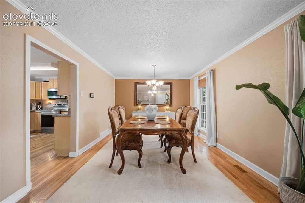 Image 6 of 42: Dining area featuring wood-finish flooring, crown molding, and a chandelier