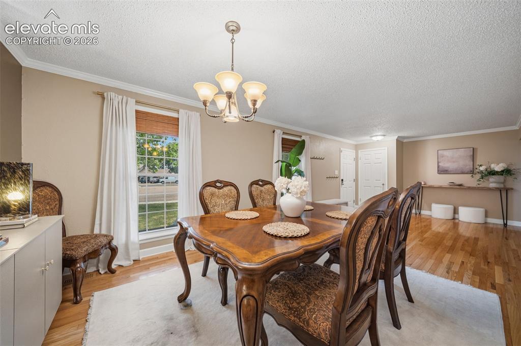 Image 8 of 42: Dining area featuring wood-finish flooring, a multi-pane window, and crown