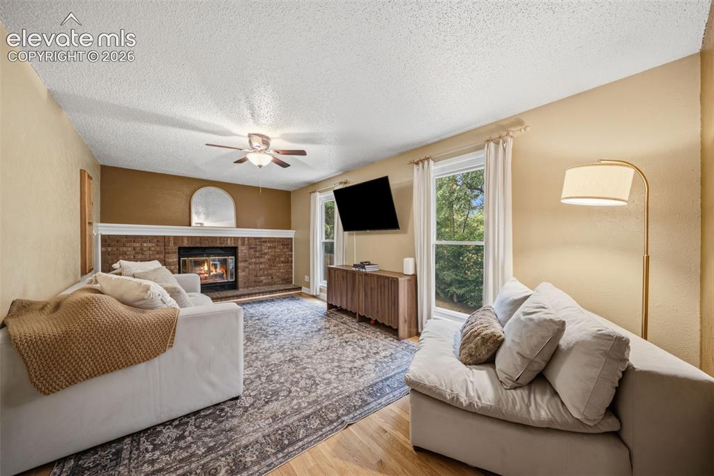 Image 9 of 42: Living space featuring a brick fireplace with a white mantel, wood-finish f