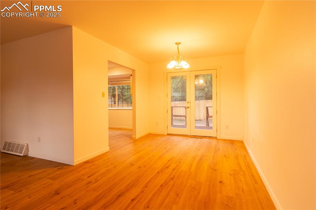 Image 11 of 47: Spare room with a chandelier, light wood-type flooring, and french doors