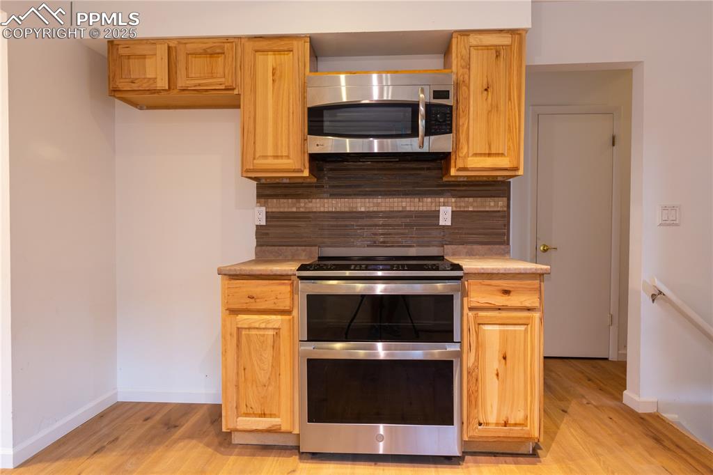 Image 13 of 47: Kitchen featuring stainless steel appliances, light wood-type flooring, tas