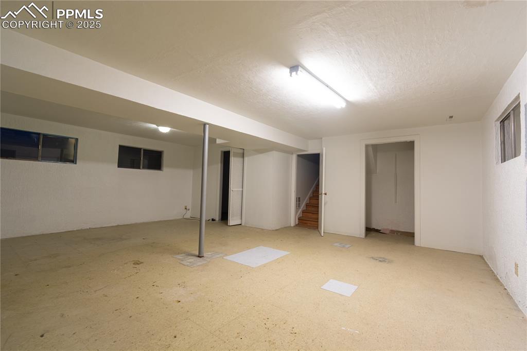 Image 44 of 47: Finished basement featuring stairs and a textured ceiling