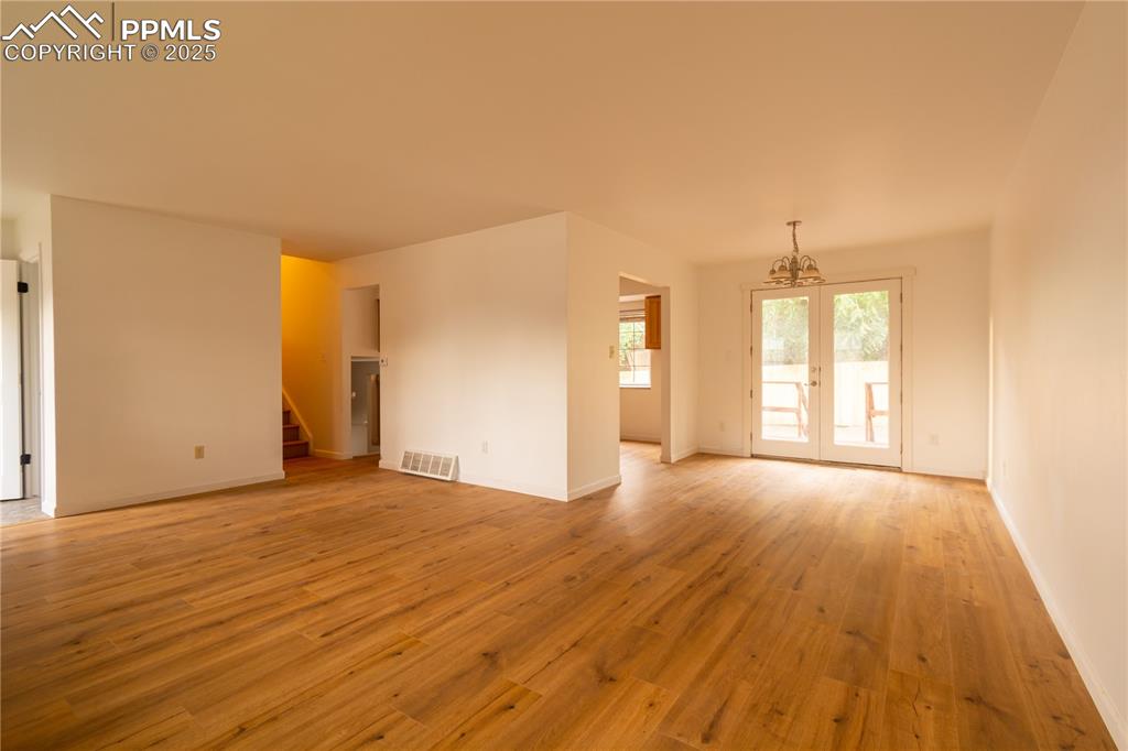 Image 6 of 47: Empty room featuring stairway, a chandelier, and light wood finished floors