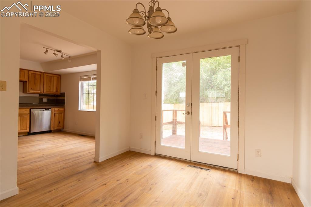 Image 8 of 47: Doorway with french doors, a chandelier, light wood finished floors, and ra