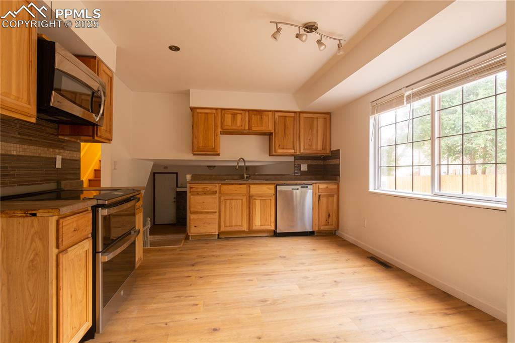 Image 9 of 47: Kitchen with appliances with stainless steel finishes, light wood-style flo