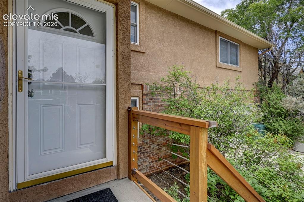 Image 10 of 43: Entryway featuring a white storm door with an arched window, wood railing w