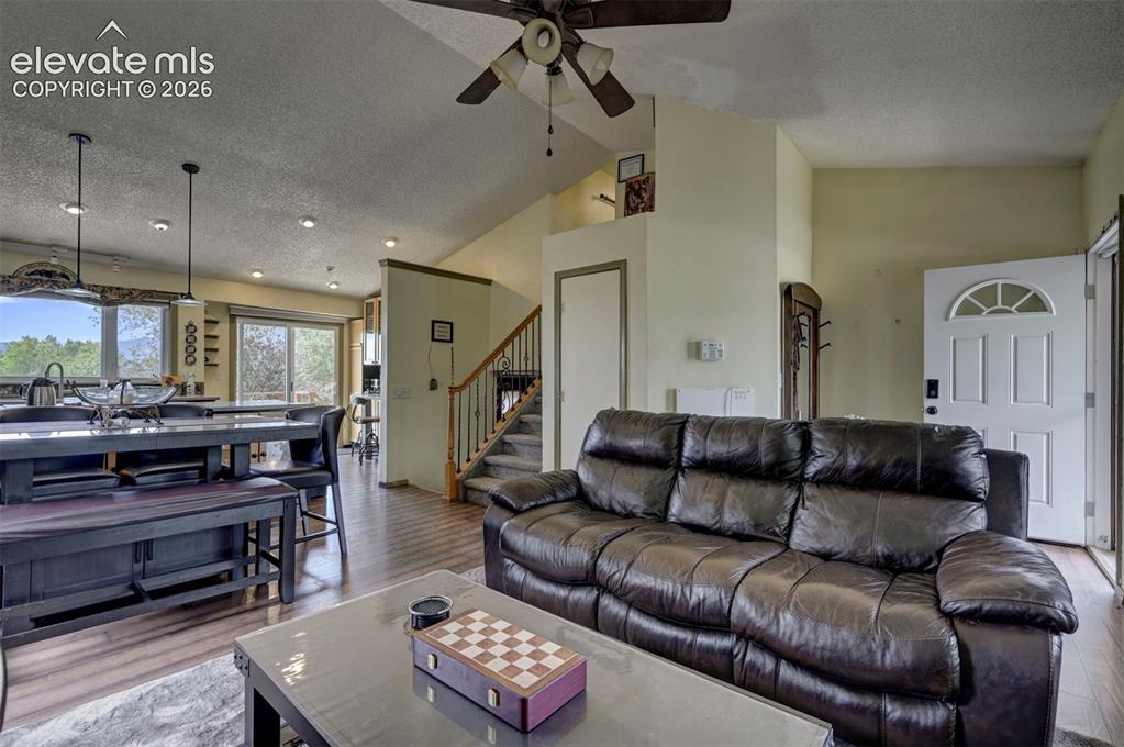 Image 13 of 43: Open-concept living area featuring wood-finish flooring, a vaulted ceiling