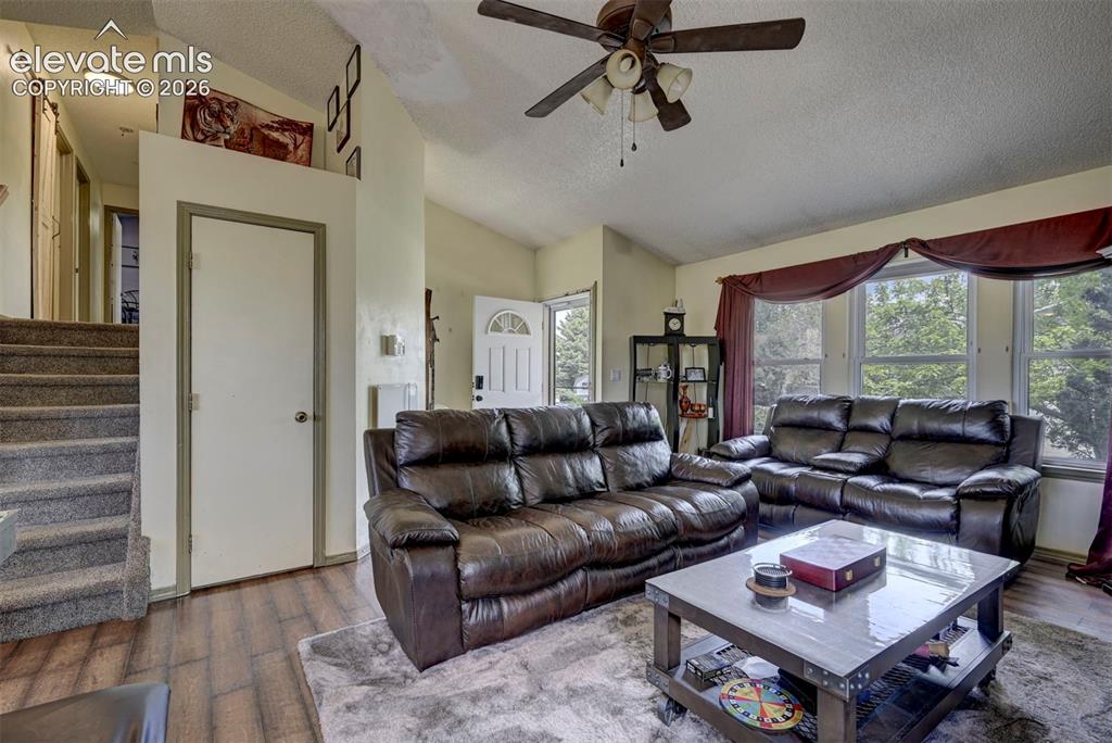 Image 14 of 43: Living area featuring wood-finish flooring, vaulted ceilings, and a ceiling