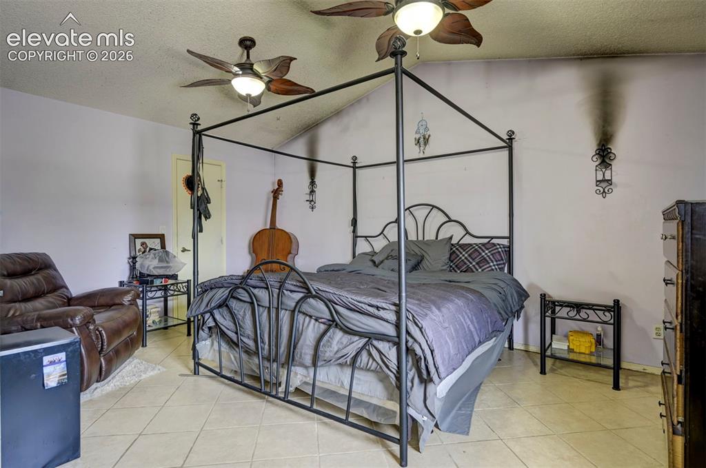 Image 22 of 43: Spacious room featuring vaulted ceilings, ceiling fan light fixtures, and n