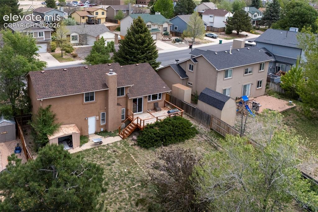 Image 41 of 43: Rear elevation featuring a spacious wooden deck with stairs to the yard, tw