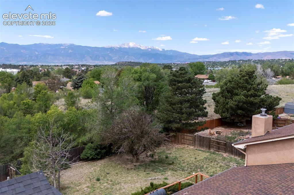 Image 42 of 43: Expansive backyard featuring a wood fence, mature trees, and natural landsc