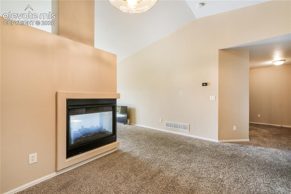 Image 22 of 50: Three sided gas fireplace between dining area and living room