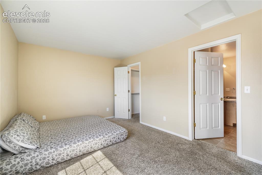 Image 30 of 50: Main level primary bedroom with walk in closets and ensuite bathroom with 2