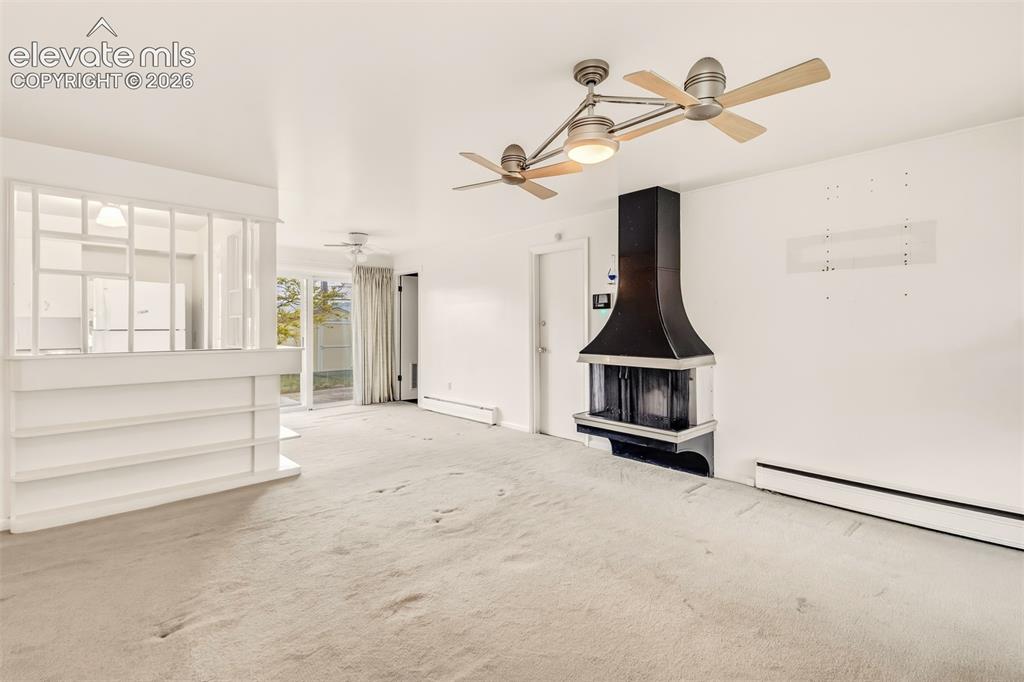 Image 3 of 25: Living room with wood burning fireplace, plenty of natural light and a walk
