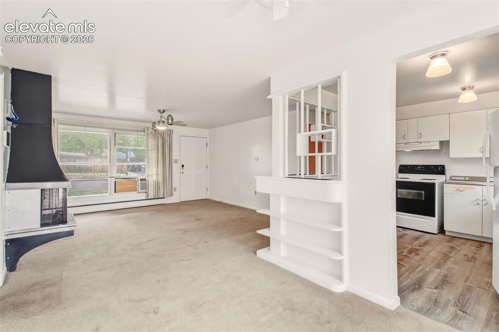 Image 4 of 25: Living room with wood burning fireplace, plenty of natural light and a walk