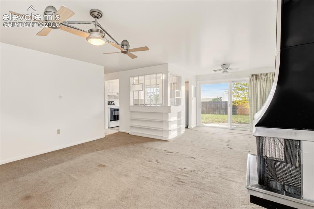 Image 5 of 25: Living room with wood burning fireplace, plenty of natural light and a walk