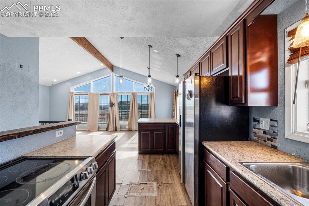 Image 4 of 12: Kitchen featuring stainless steel appliances, light wood-style floors, dark