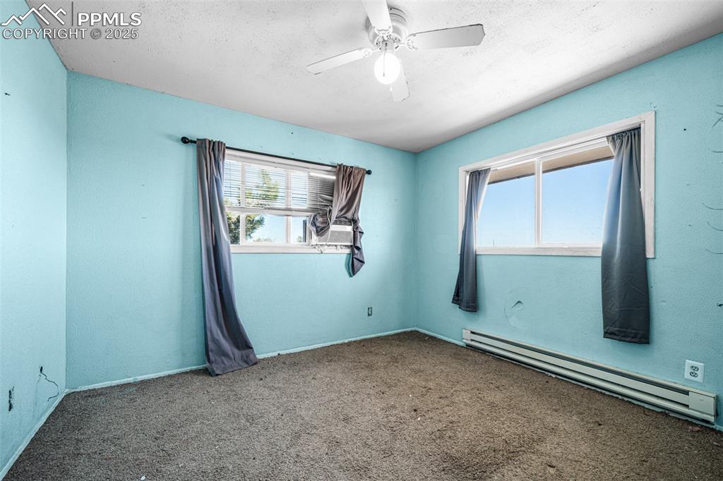 Image 7 of 12: Carpeted spare room featuring baseboard heating, a ceiling fan, and a textu