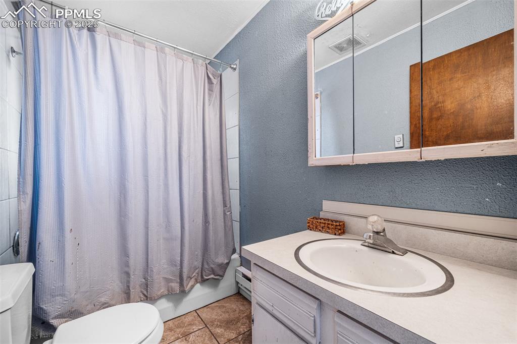 Image 8 of 12: Bathroom featuring a textured wall, vanity, tile patterned flooring, shower