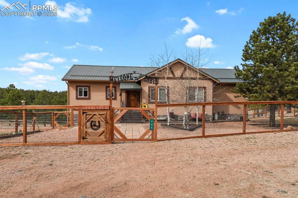 Image 1 of 41: Chalet / cabin featuring a gate, a metal roof, and stucco siding