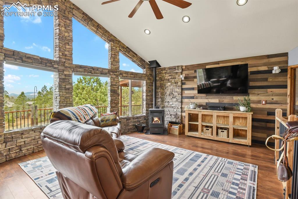 Image 13 of 41: Living room featuring ceiling fan, a wood stove, dark wood-style flooring,