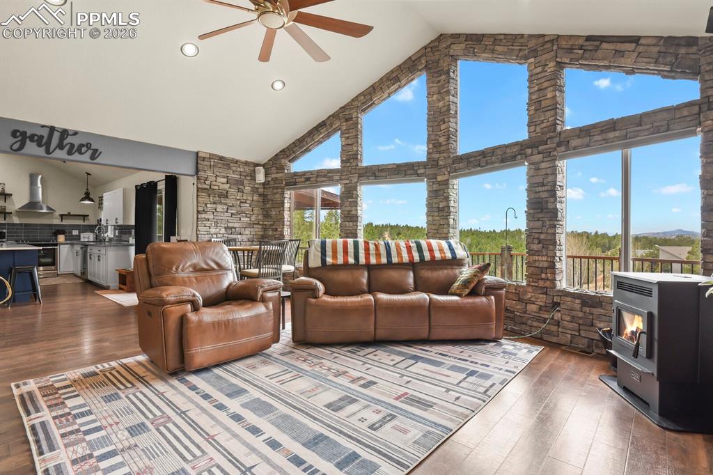 Image 14 of 41: Living room featuring a ceiling fan, Pellet-Stove, Wood flooring, and a hig