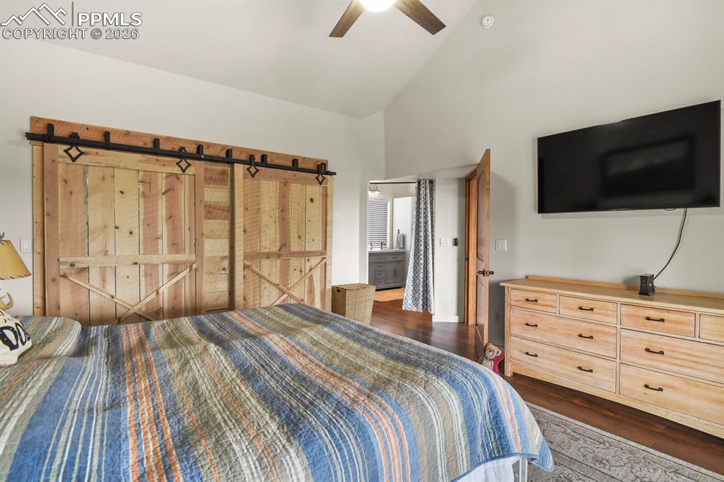 Image 17 of 41: Bedroom with vaulted ceiling, dark wood-style flooring, a ceiling fan, a ba