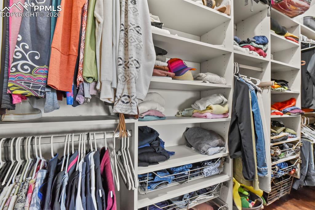 Image 18 of 41: California Walk in closet with wood finished floors